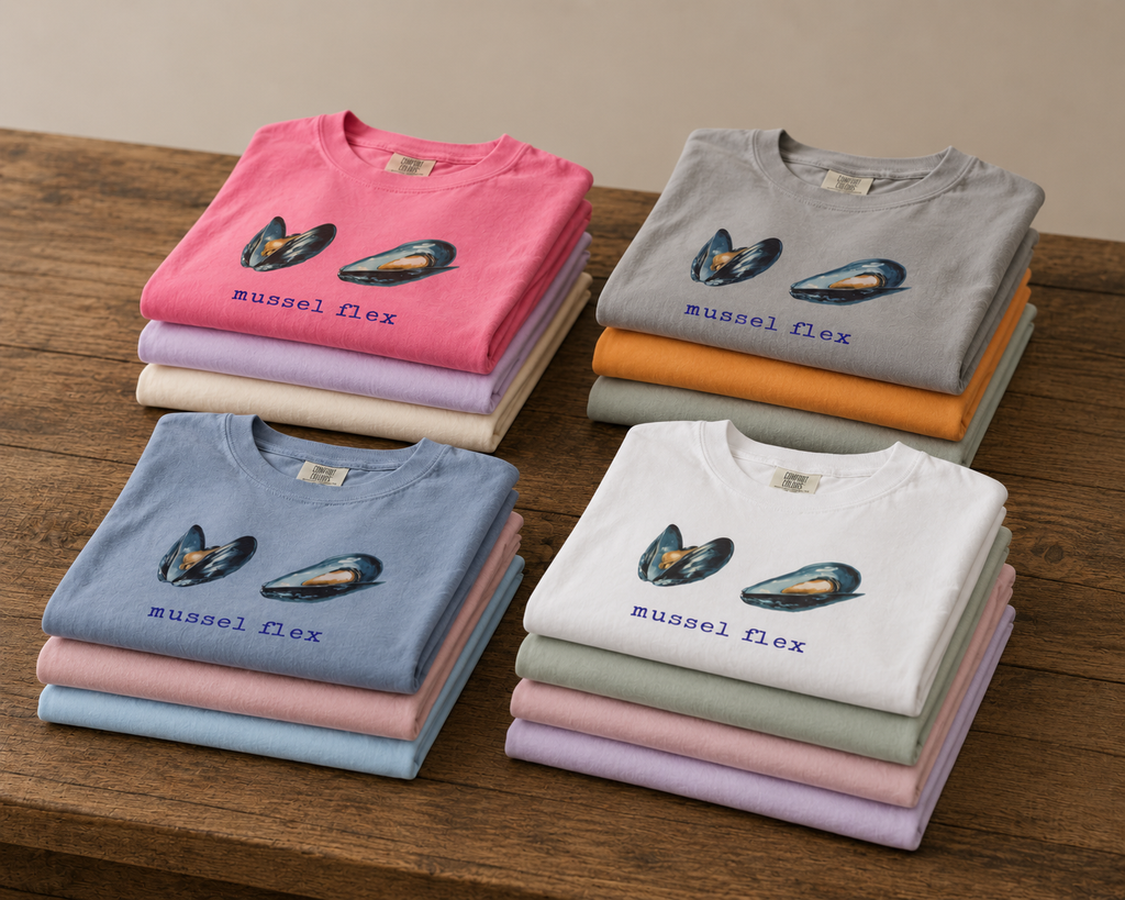 Stacks of folded t-shirts in various colors with 'mussel flex' text on a wooden surface.